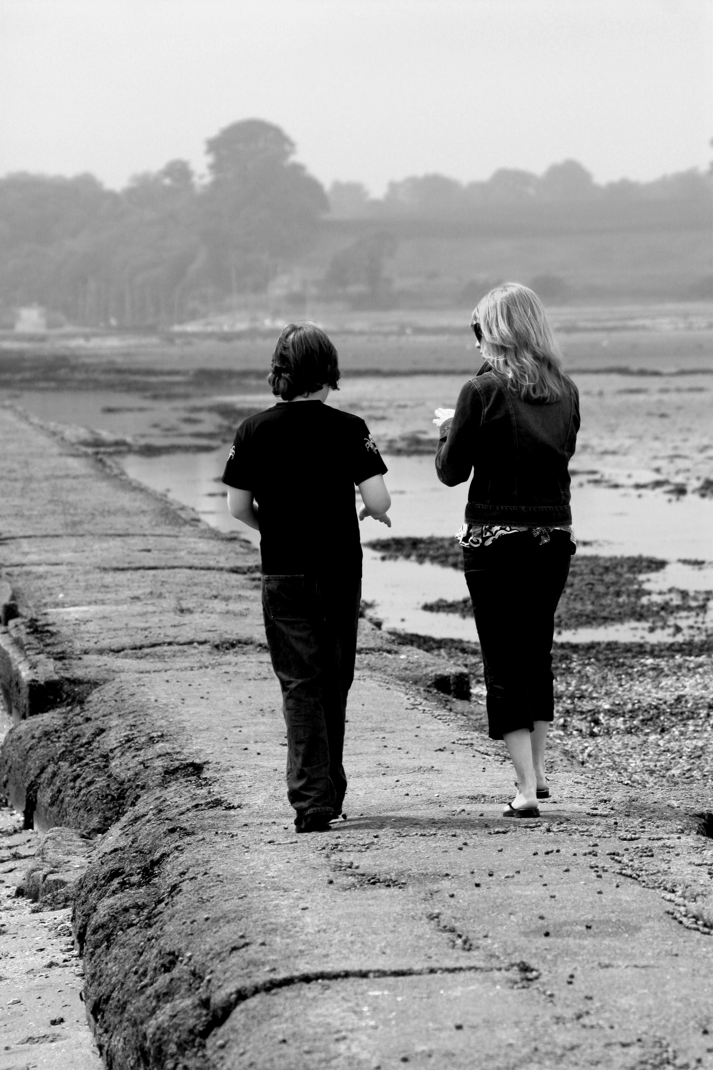 two people walk along a sea wall